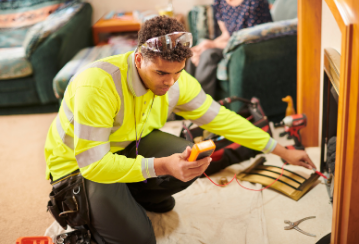 A fireplace inspector uses an electronic tool to inspect a fireplace in someone's home.